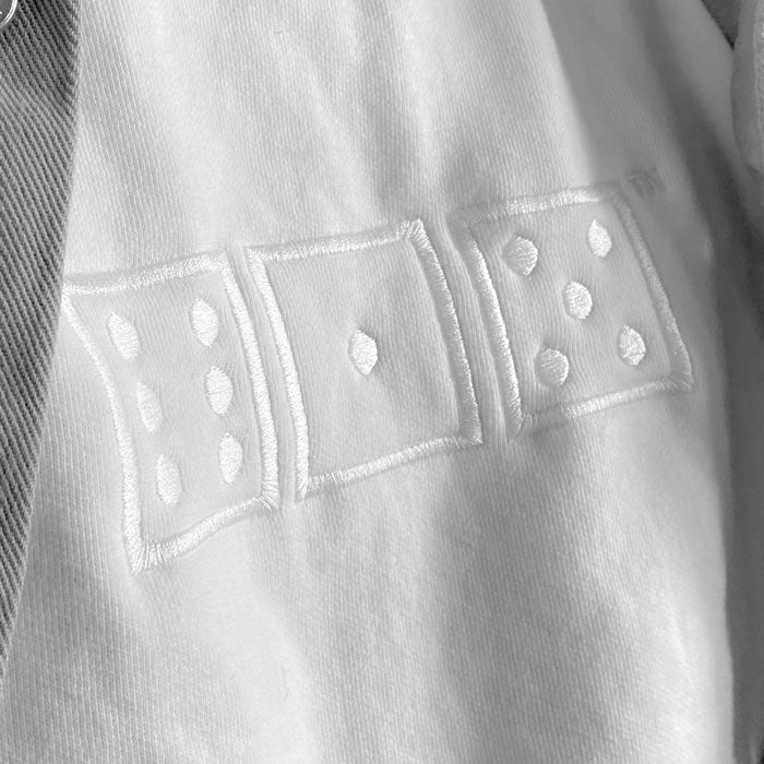 A closeup photo of the white embroidery on a white sweatshirt. The embroidery design is of three white squares that look like game dice. The dice show numbers six, one, five. 615 is the telephone area code for Nashville, Tennessee, USA.