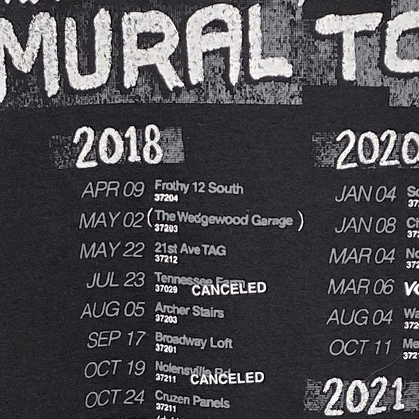 Close up look at the back side artwork. Mural in white at the top and dates listed below with mural locations. The artwork is layered and distressed to look like a worn band tee.