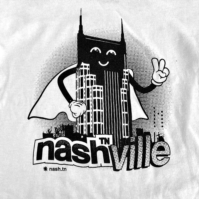 Close up look at a black and white Tshirt design. The Nashville Batman building is styled as a superhero wearing a cape and making a peace sign with his cartoon hand. It appears that he is standing over a sign that reads nashᵀᴺ ville.