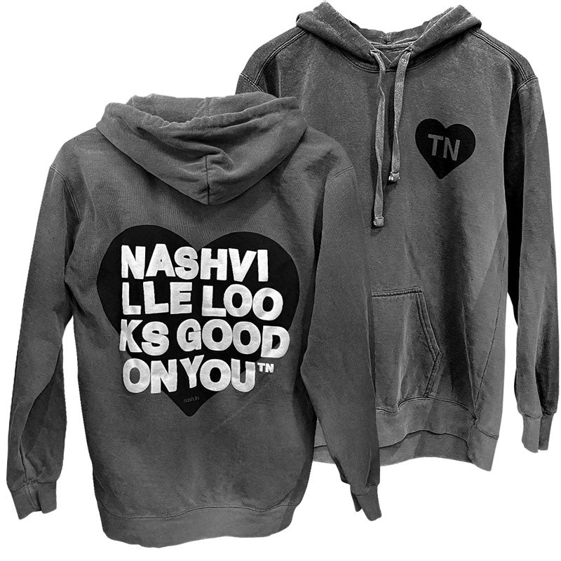Back and front sides of gray hooded sweatshirt on a white background. Backside has a black heart with white text printed on top that reads nashville looks good on youᵀᴺ in wrapped text. The front side of hoodie has a small black heart with letters TN on chest. TN is the abbreviation of Tennessee.  