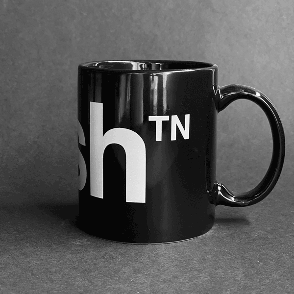 Spinning video of black nashᵀᴺ  coffee mug on gray background. The black mug has a white nashᵀᴺ logo on the front. Nash is short for Nashville and TN is the abbreviation for Tennessee. 