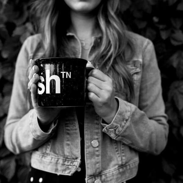 Lady holding black campfire mug with white text. 