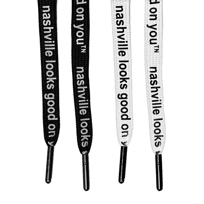 Four laces with dark metal tips on a white background. Two black laces with white letters on the left and two white laces and black text on the right. On each lace, nashville looks good on youᵀᴺ is printed.  