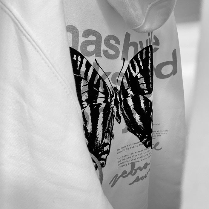 Close up image of black swallowtail butterfly printed on backside of an off-white color sweatshirt hoodie