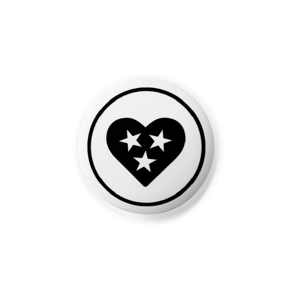 White round lapel pin button on a white background. There is a black circle around a black heart. The heart has three white stars in the center. The stars are for Tennessee's three grand divisions: East, Middle and West. Tennessee is known as the Tri-Star state.