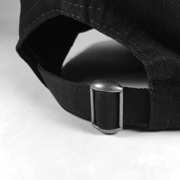 Close up of adjustable metal sizing buckle on a black baseball cap.
