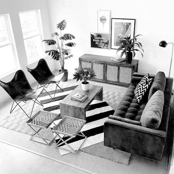 Angled view of a living room  looking from above. There are two chairs on the left, a large dark sofa on the right with a light colored table in between. There are three framed prints hanging on the wall/ 