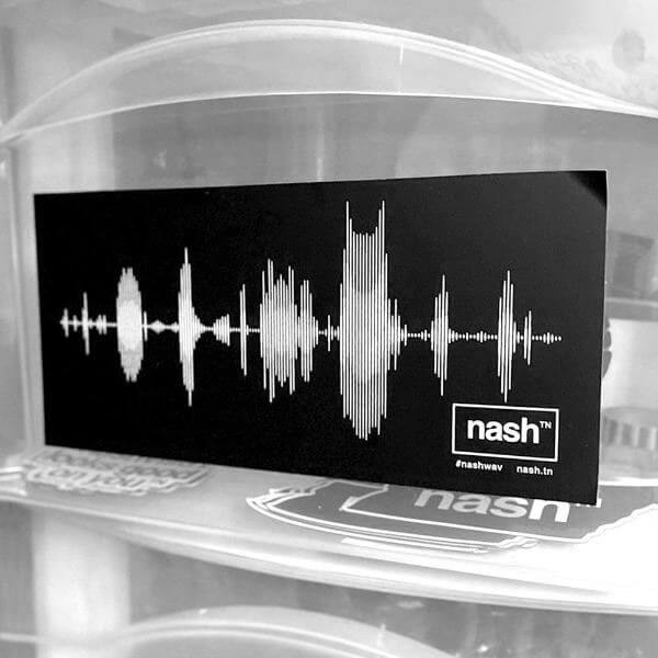 Black rectangle affixed to a see through surface.  A white, stylized audio wav file mimics the Nashville, Tennessee skyline with the Batman Building most prominent. The nashᵀᴺ  logo inside of a rectangle is printed at the lower right corner.
