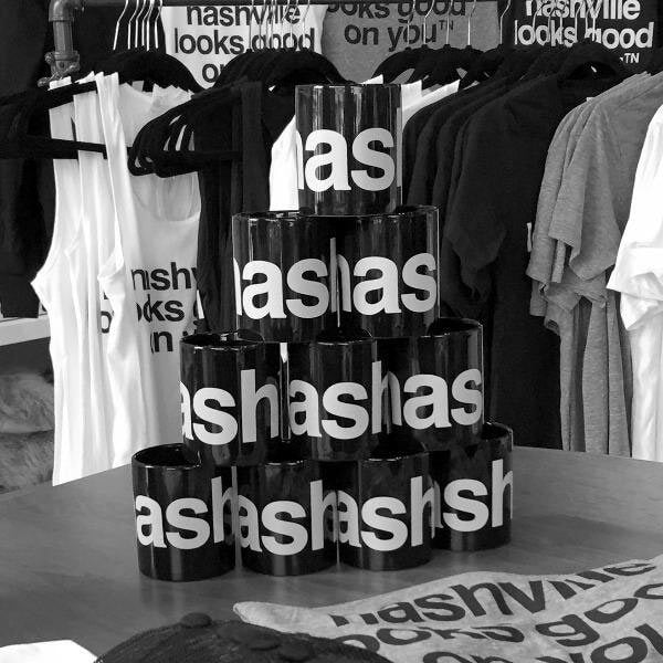 Tall stack of black coffee mugs with white nashᵀᴺ  text surrounded by nashville looks goodᵀᴺ   on you merchandise.