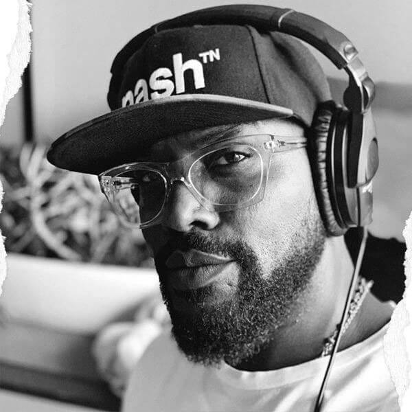 Man with beard and clear glasses wearing headphones. He is wearing a black baseball cap with a camouflage flat bill visor. The hat has the nashᵀᴺ embroidered in white on the front.