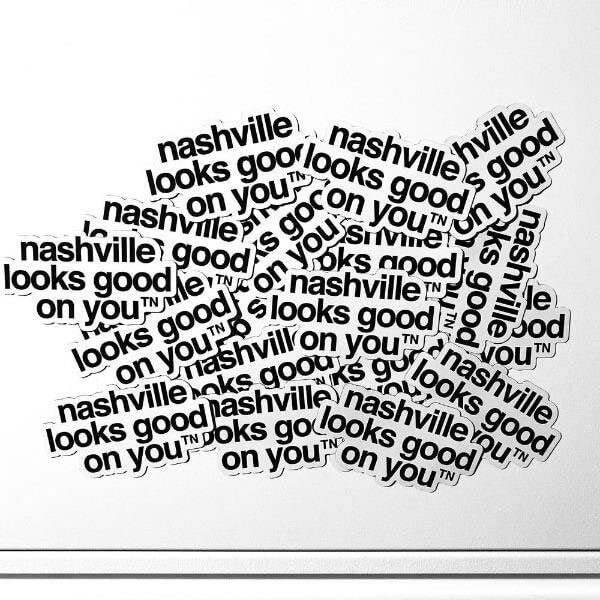 A messy jumble of white magnets with black text on a white filing cabinet. The magnets are layered on top of each other. They each say nashville looks good on youᵀᴺ in black.