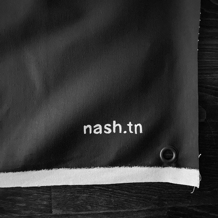 Up close image showing unfinished edge of canvas, grommet and artist's mark: nash.tn