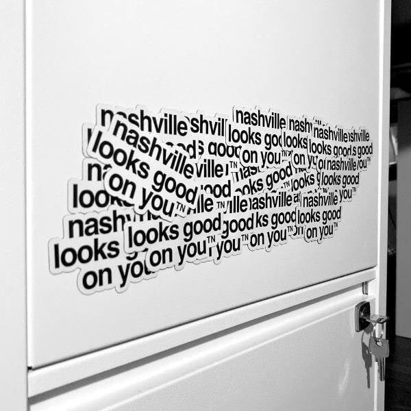 A jumble of white magnets with black text on a white filing cabinet. The magnets are layered on top of each other and the overall shape looks similar to Tennessee's state shape.
