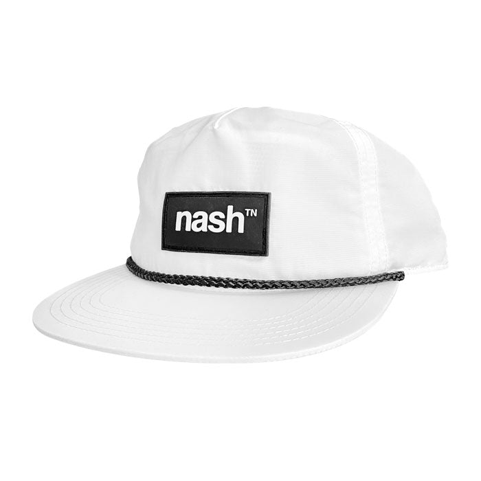 Angled view of white baseball cap with black rope and black patch on white background. The hat has a flat bill and is pointed toward the left. Black rectangle patch on center of hat has white nashᵀᴺ logo.
