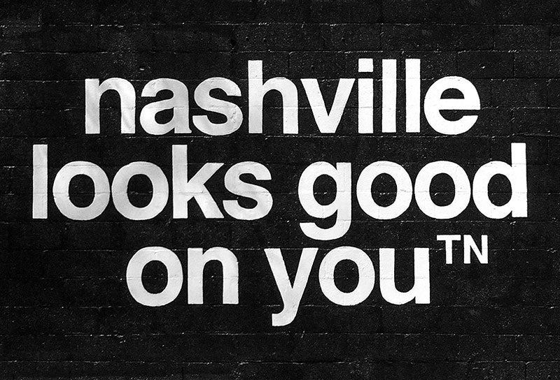 Photo of a nashᵀᴺ mural. A black, painted block wall with nashville looks good on  youᵀᴺ  in white. 