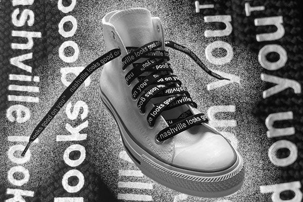 White hightop sneaker on a black and white text background. Each shoelace is black with white printed letters. On each lace, nashville looks good on youᵀᴺ is printed.